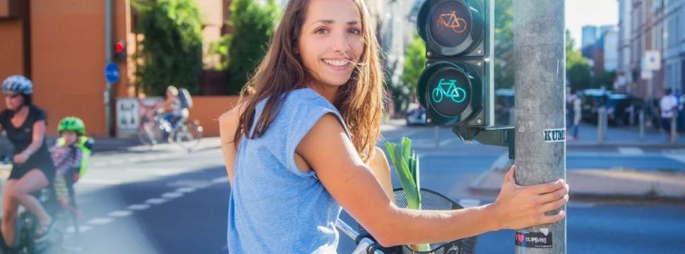 Frau auf dem Fahrrad wartet an einer Ampel