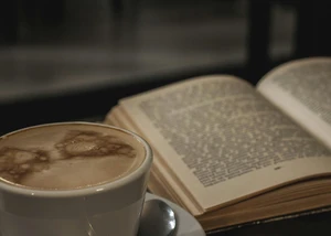 Ein aufgeklapptes Buch und ein Kaffee
