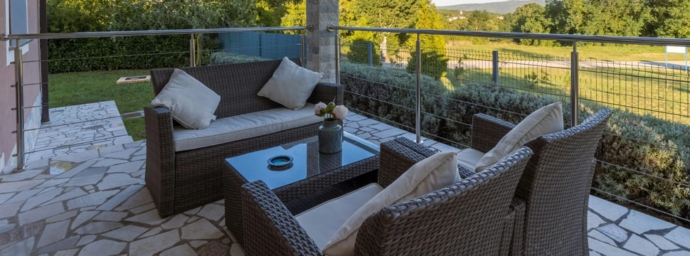 Braune Korbstühle mit Gartentisch auf einer gefliesten Terrasse