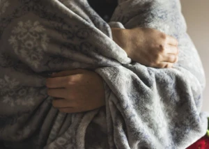 Hände, die unter einer Wolldecke hervorschauen