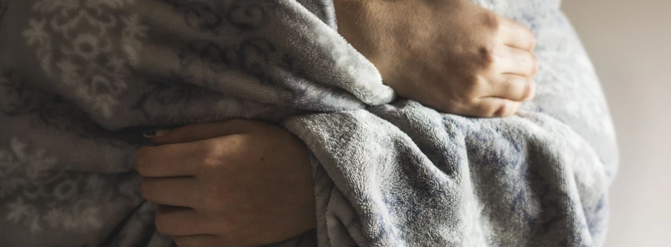 Hände, die unter einer Wolldecke hervorschauen