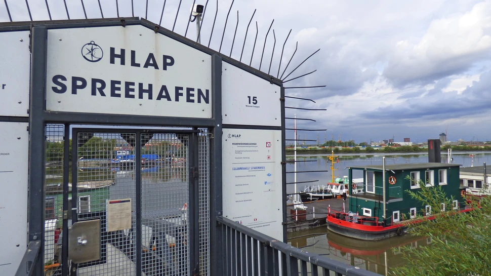 weißes Eingangstor zum Spreehafen, im Hintergrund ein grünes Schiff