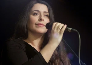 eine dunkelhaarige Sängerin hält eine Hand an ein Mikrofon