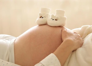 Eine Schwangere hält Baby Schuhe auf ihren Bauch