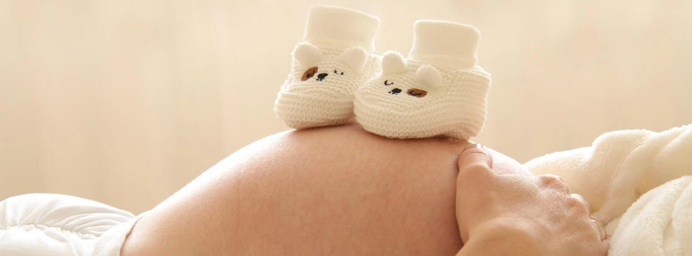 Eine Schwangere hält Baby Schuhe auf ihren Bauch