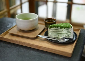 Matcha-Crêpe-Kuchen mit Genmaicha Uji Latte in der japanischen Keramikschale