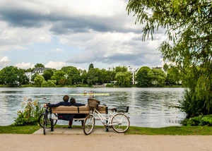 Ein Pärchen sitzt auf einer Parkbank direkt an der Hamburger Alster
