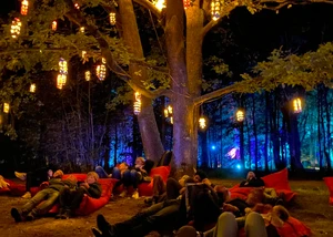 Menschen liegen auf Kissen in einem beleuchteten Park