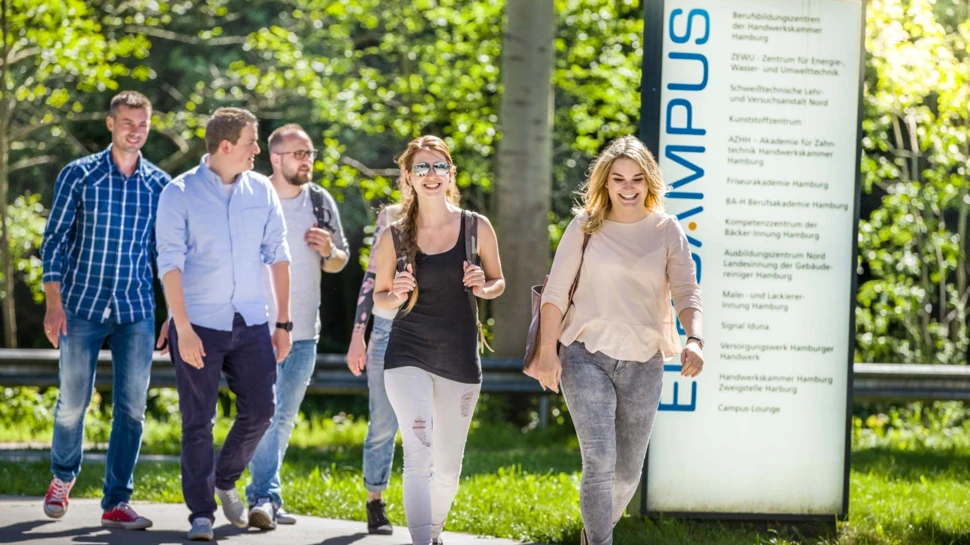 fünf Personen gehen über das sommerliche Gelände vom Elbcampus