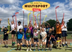 Kinder mit Hockeyschlägern auf einem Sportplatz