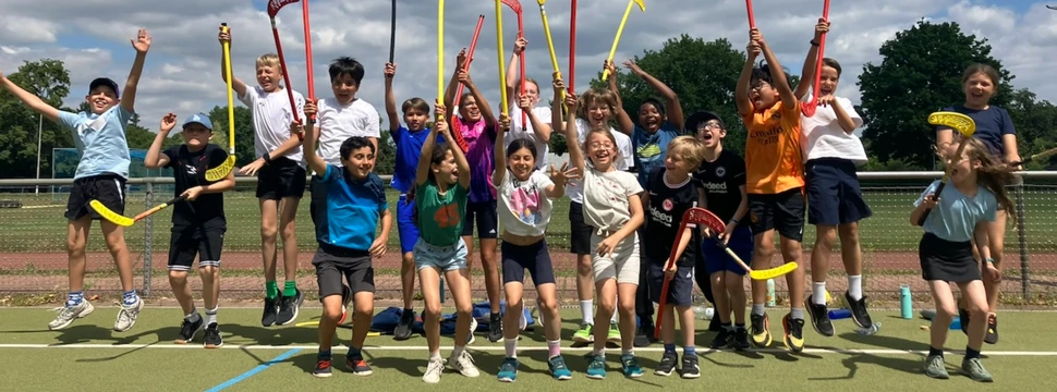 Kinder mit Hockeyschlägern auf einem Sportplatz