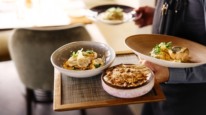 Galerie-Bild 6: Eine Person, die 4 Teller trägt, die serviert werden sollen