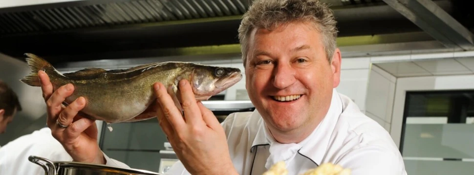 Koch Heinz O. Wehmann mit einem ganzen Fisch in der Hand