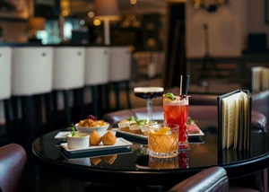 Edle Coctails und kleine Speisen auf einem braunen Tisch in einer Bar