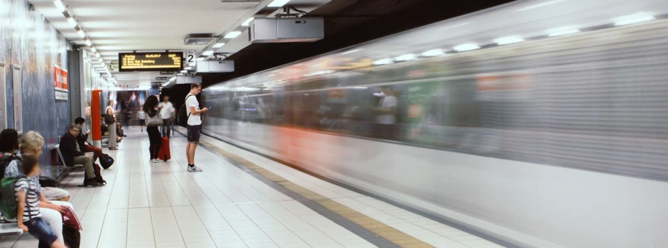 Personen auf einem Bahnsteig und vorbeifahrende U-Bahn