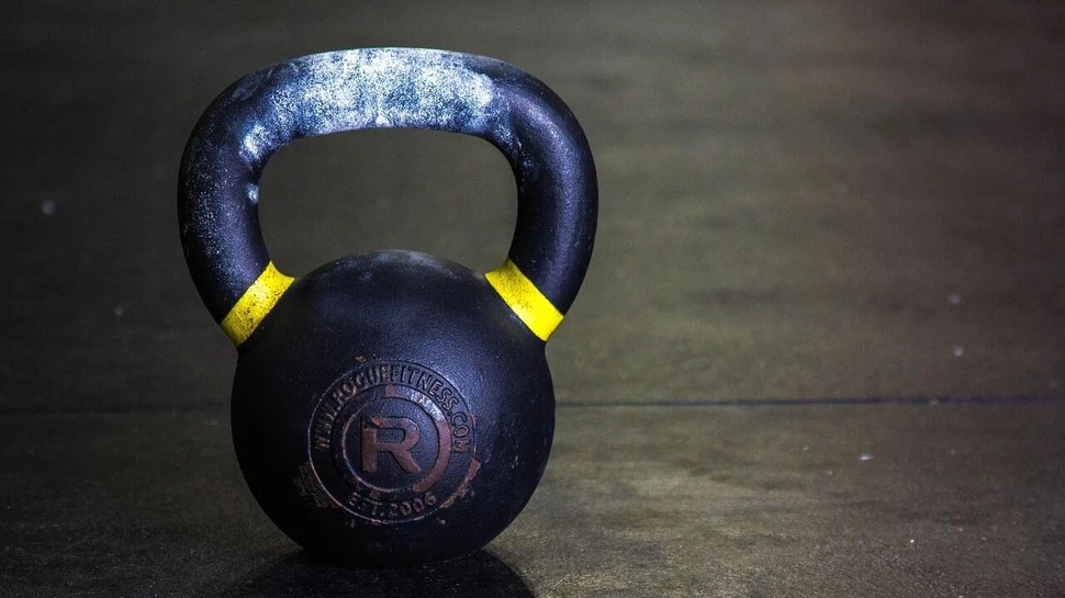eine Kettlebell mit Kreide am Griff steht auf dunklem Boden