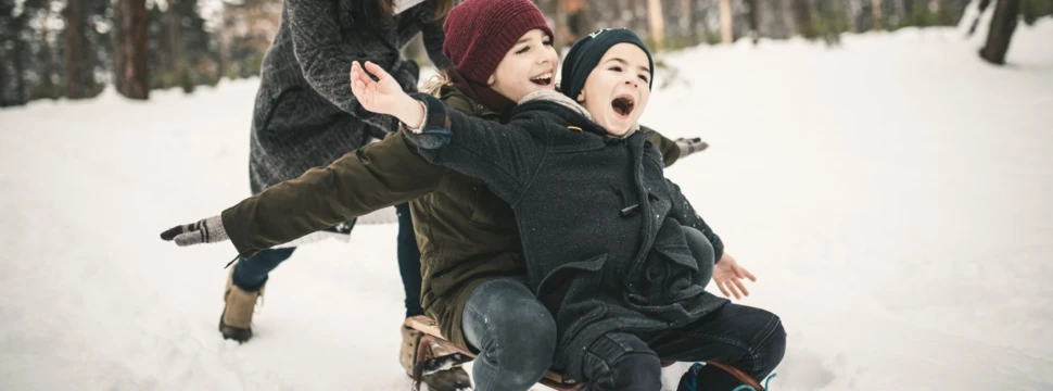 Mutter schiebt Kinder auf einem Schlitten