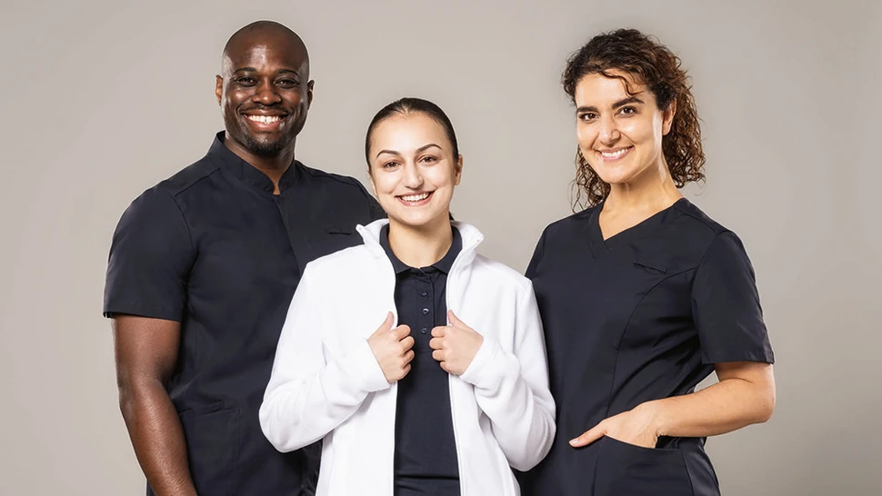 3 Menschen tragen Arbeitskleidung im MedCare Bereich