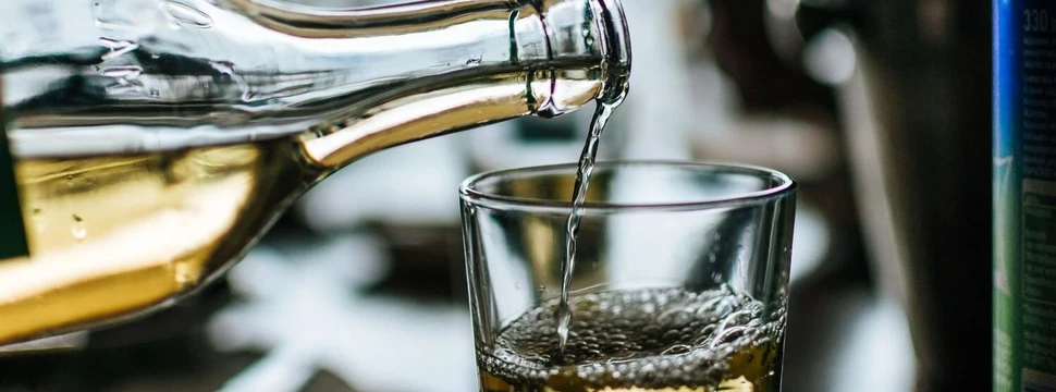Weißwein Aus einer Flasche wird Weißwein in ein Glas eingefüllt