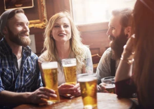 Zwei Frauen und zwei Männer trinken Bier in einer Kneipe