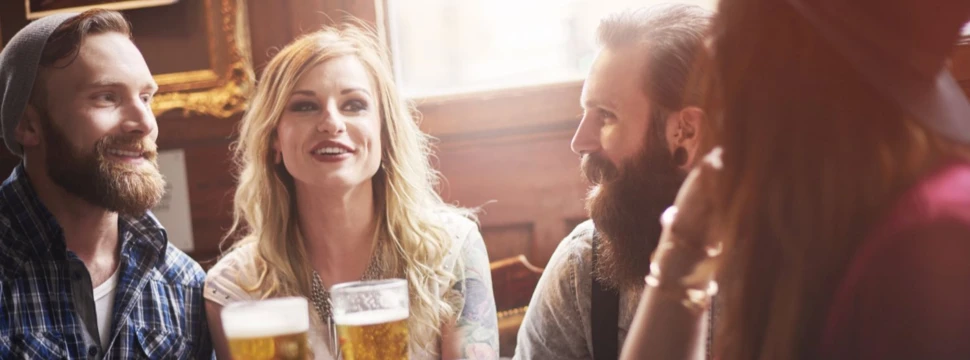 Zwei Frauen und zwei Männer trinken Bier in einer Kneipe