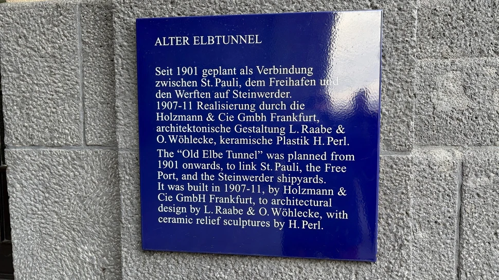 Blaue Hinweistafel mit weißer Schrift zum geschichtlichen Hintergrund des Alten Elbtunnels