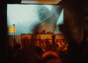 Paul Kalkbrenner am DJ-Pult, hinter ihm eine Leinwand, vor ihm Konzertbesucher