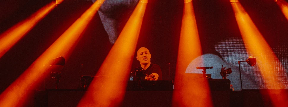 Paul Kalkbrenner am DJ-Pult im roten Scheinwerferlicht