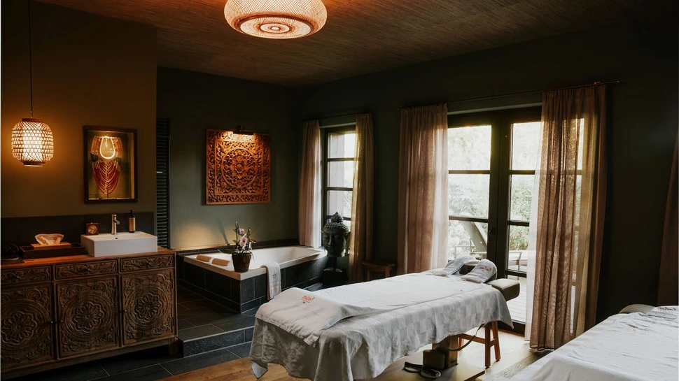 balinesisch eingerichteter Massageraum mit Badewanne und Massageliegen