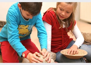 Kinder beim Kornmahlen