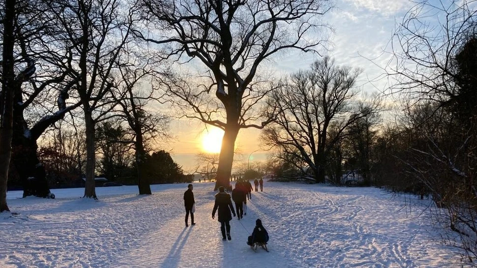 Spaziergänger im Schnee vor der untergehenden Sonne