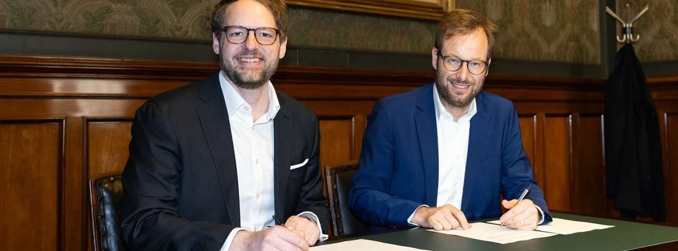 zwei Männer im blauen Anzug unterschreiben einen Vertrag