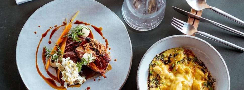 weiße Teller mit verschiedenen Gerichten auf einem Holztisch