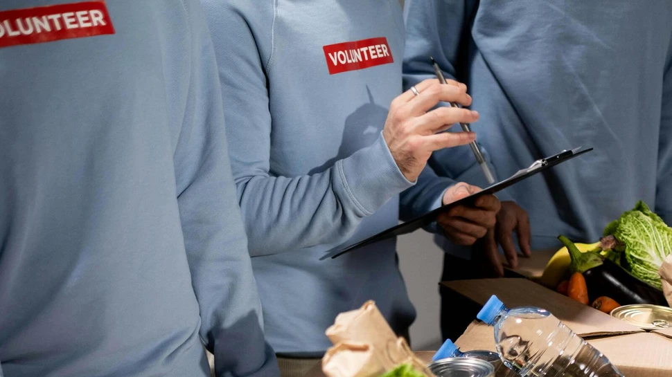 Freiwillige Helfer mit blauen Pullovern an einer Lebensmittel-Ausgabe