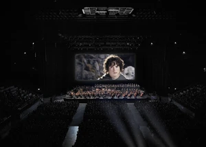 Große Kinoleinwand vor der ein großes Orchester aufgestellt ist