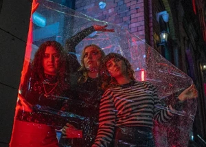 Drei Frauen, die in einem Fensterrahmen für ein Foto posieren und dabei angeleuchtet werden