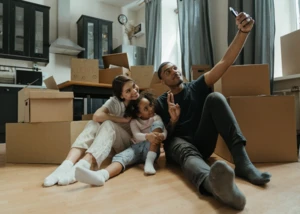 Familie feiert Einzug mit Selfie in der neuen Wohnung. Glückliche Familie macht Selfie zwischen Umzugskartons in neuer Wohnung