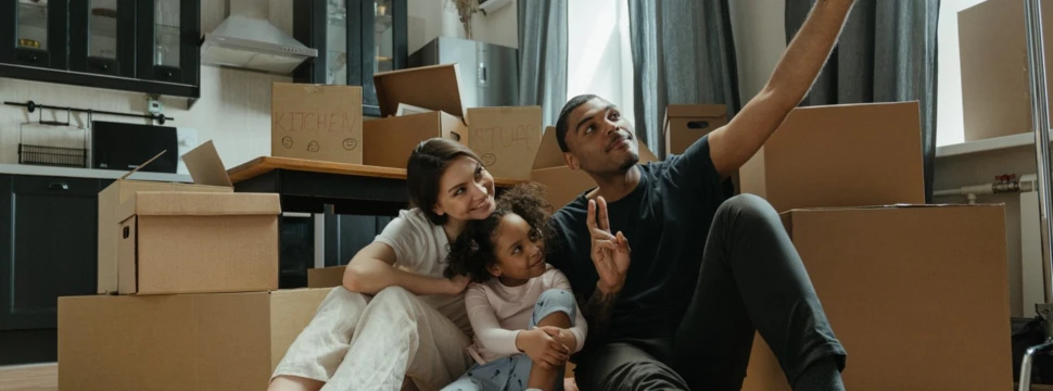 Glückliche Familie macht Selfie zwischen Umzugskartons in neuer Wohnung