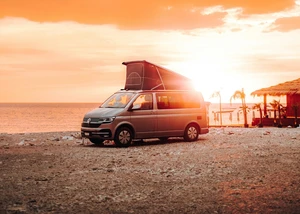 Camper mit geöffneter Seitentür steht am Meer
