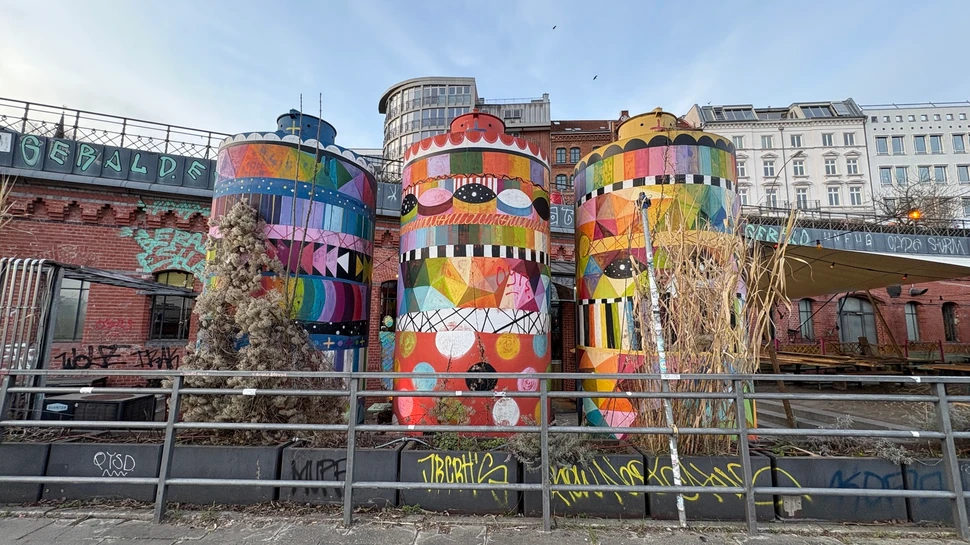 Bunte hohe Tonnen vor einem Backsteingebäude