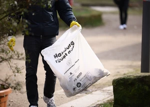 Eine männliche Person mit einer Mülltüte in der Hand