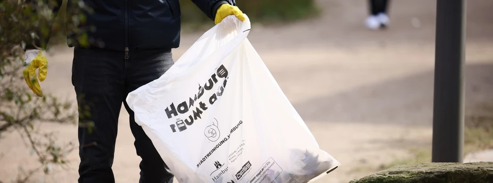 Eine männliche Person mit einer Mülltüte in der Hand