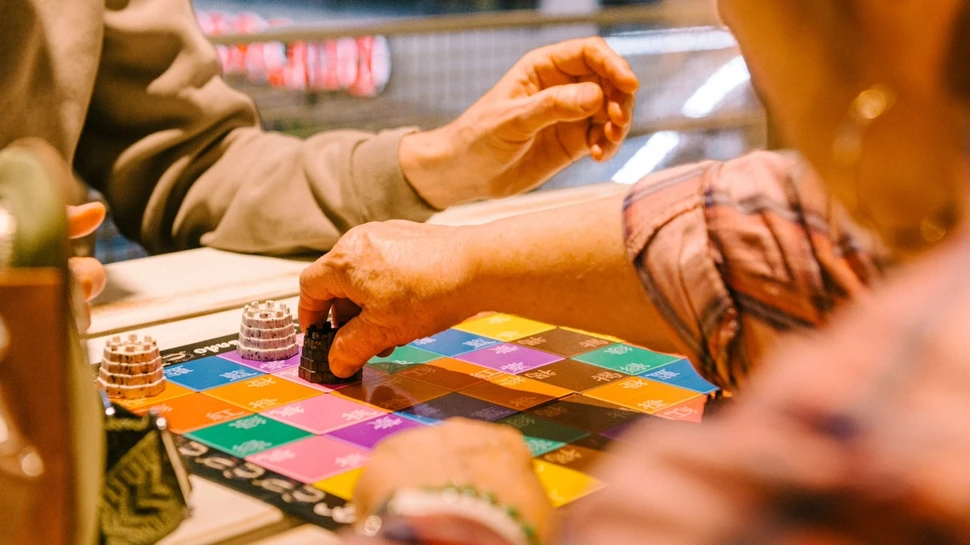 Man sieht die Hände von zwei Personen, die zusammen Gesellschaftsspiele spielen