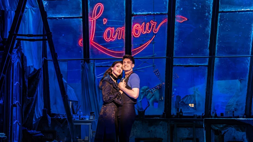 ein junges Paar steht dicht beieinander, im Hintergrund der Schriftzug L'amour