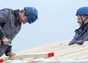 Zwei Mitarbeiter der Horst Stelter GmbH schrauben Holzlatten auf die Dachkonstruktion.