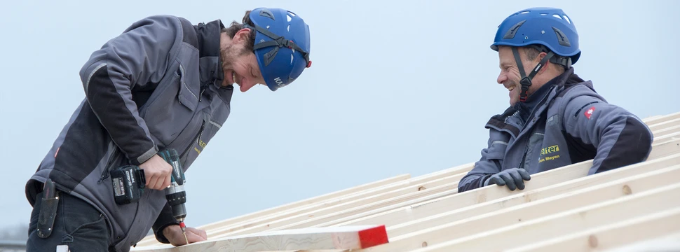 Zwei Mitarbeiter der Horst Stelter GmbH schrauben Holzlatten auf die Dachkonstruktion.