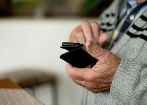 Ein Senior hält ein schwarzes Smartphone in der Hand
