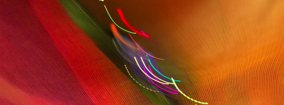 Lichtinstallation mit leuchtenden Linien in warmen Farben wie Rot, Orange und Grün, die Bewegung und Kreativität symbolisieren.