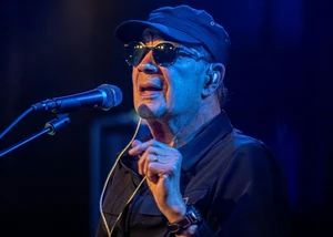 Der Sänger Mitch Ryder mit Sonnenbrille und Mütze am Mikro