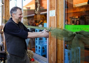 Ein Mann mittleren Alters schneidet mit einer Schere eine Schleife für eine Wiedereröffnung eines Ladens durch